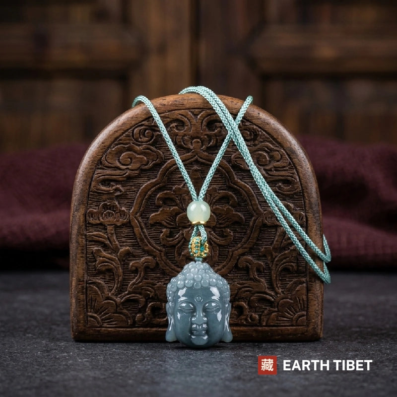 Jadeite Buddha head pendant on a mint green cord against a carved wooden panel