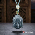 Buddha head pendant hanging, showing the dark face and paler grey-green curls