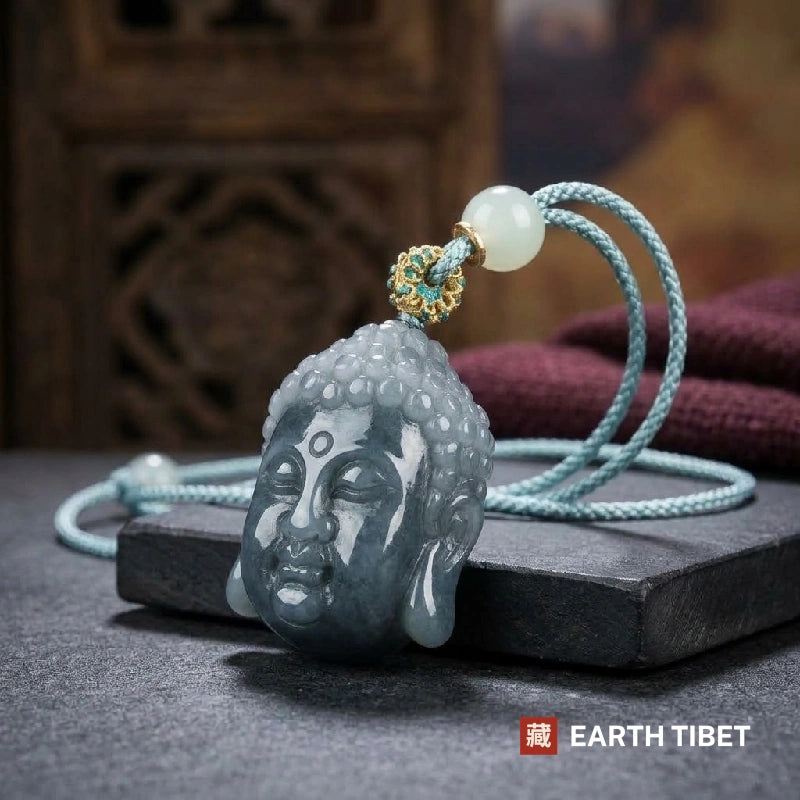 Three quarter view of the jadeite Buddha head with its enamelled gold bail and celadon jade bead