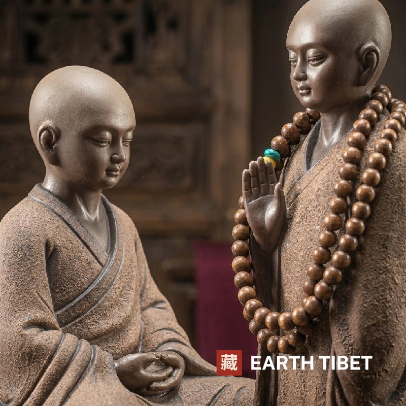 Close view of the seated monk's lowered face and the standing monk's raised palm