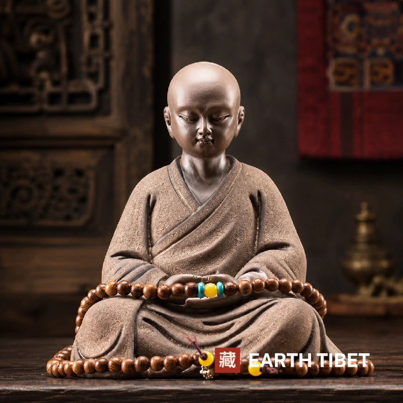 Seated little monk statue from the front, hands resting in the meditation seal