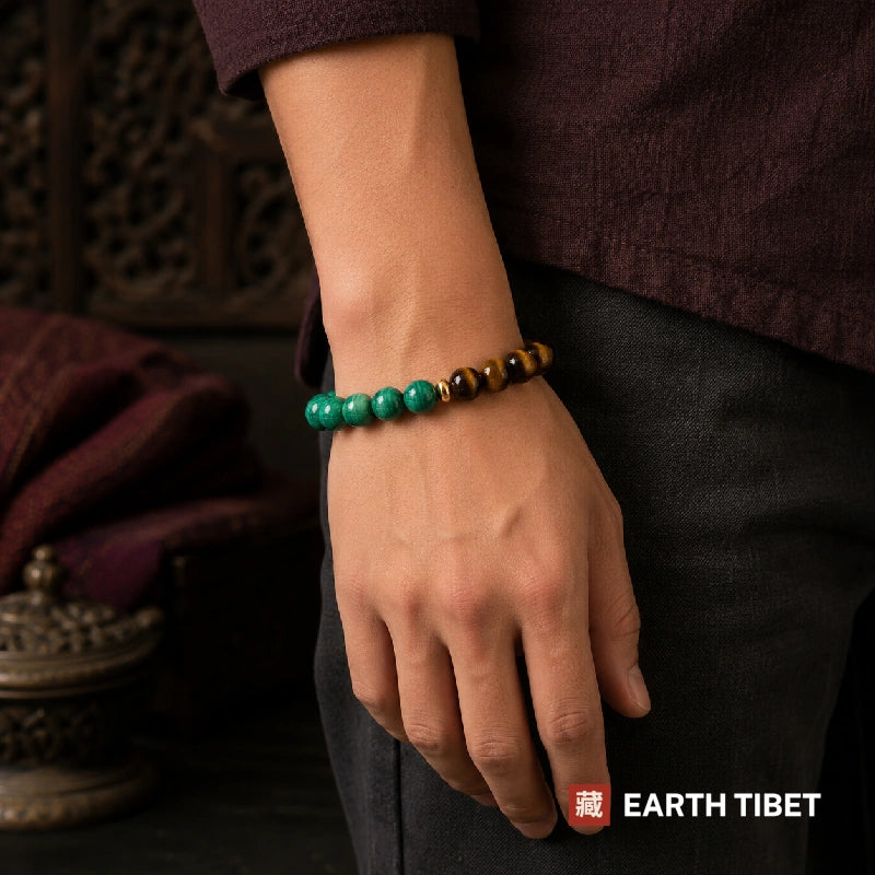Malachite and tiger eye bracelet worn on a wrist below a maroon sleeve