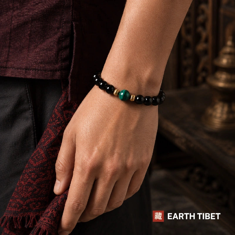 Tourmaline and malachite bracelet worn on a wrist below a maroon sleeve