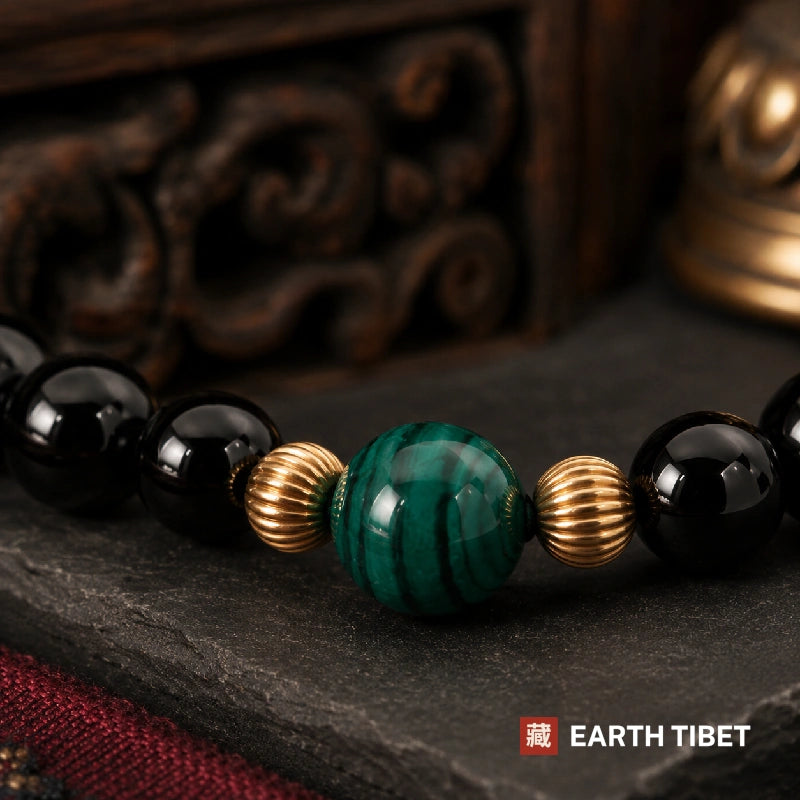 Macro of the malachite bead and gold rings against polished black tourmaline