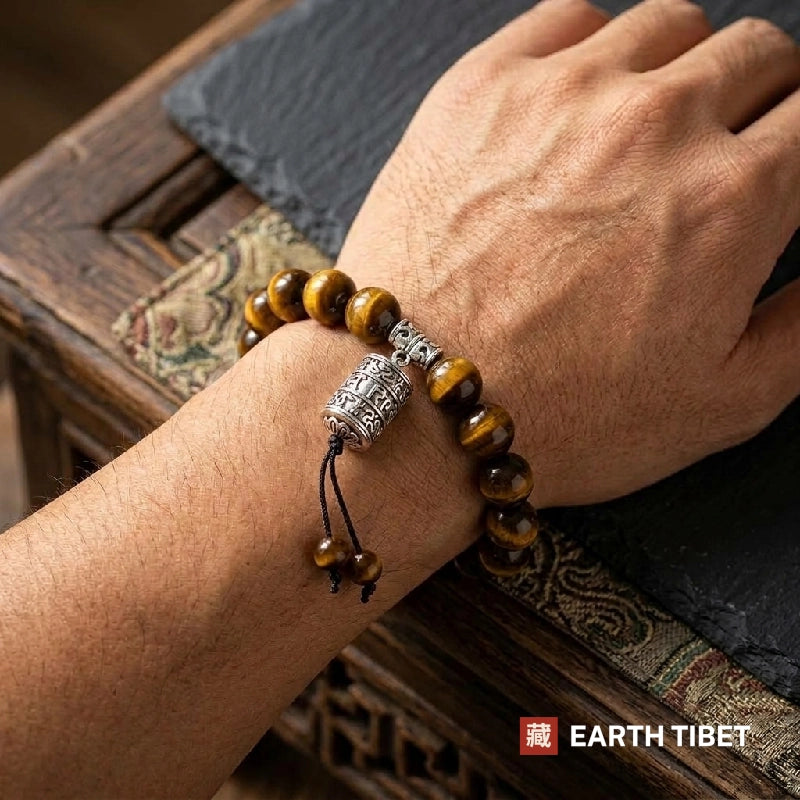 Tiger eye bracelet worn on a man's wrist beside a carved wooden chest