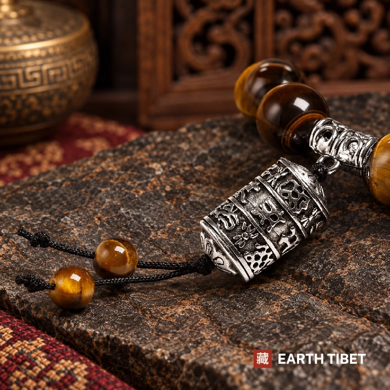 Detail of the engraved Tibetan script on the silver mantra barrel and its cord beads