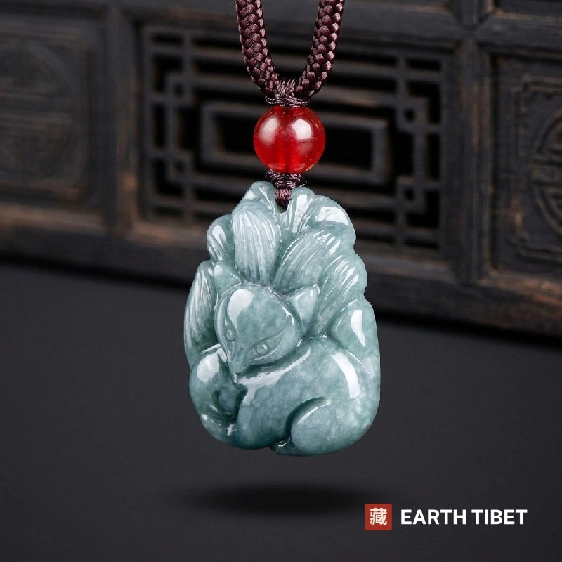 Jadeite nine-tailed fox pendant on its braided cord with a red agate bead above it