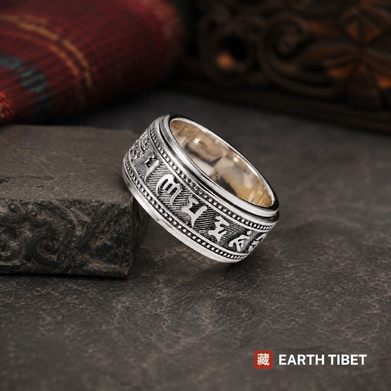 Tibetan silver spinner ring resting on slate, showing the beaded borders either side of the turning band
