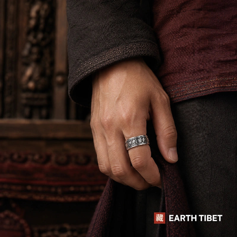 Om mani padme hum spinner ring photographed against carved wood and red textile