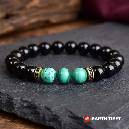 Black onyx bracelet with three malachite beads and antiqued brass rondelles on slate