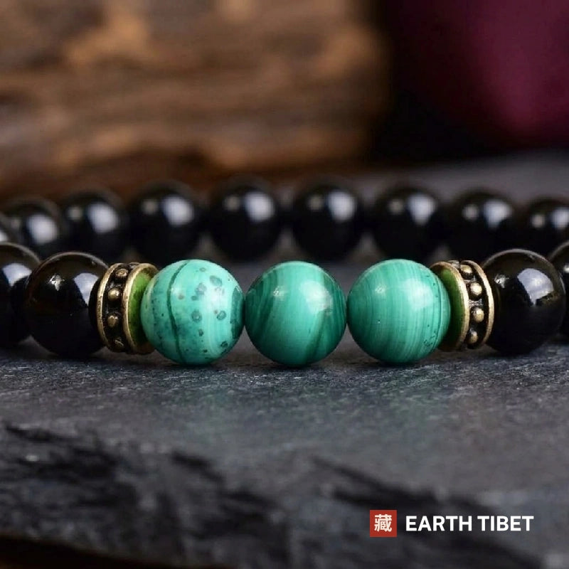 Close view of three banded green malachite beads between antiqued brass spacers