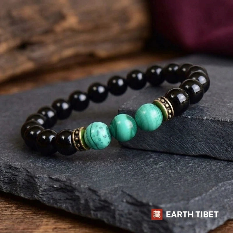 Black onyx and malachite stretch bracelet resting against dark slate