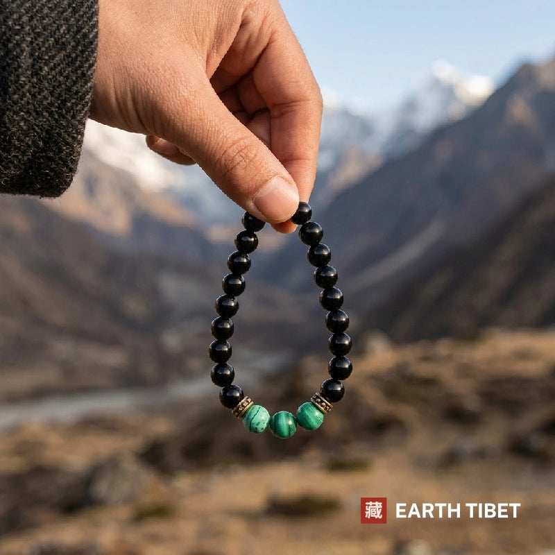Black onyx malachite bracelet held up in front of Himalayan mountains