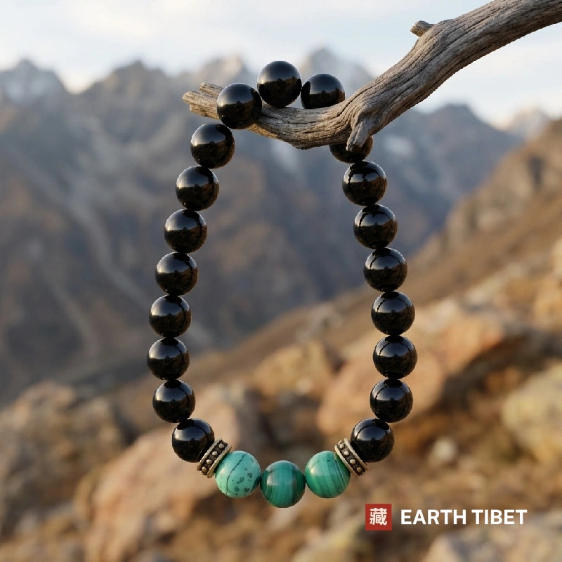 Onyx and malachite bracelet hanging from a weathered branch in the mountains