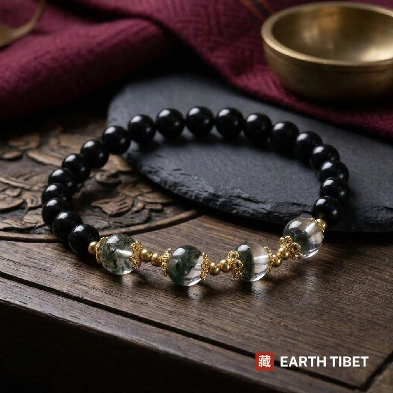 Green phantom quartz and black obsidian bracelet with gold filigree caps on dark wood