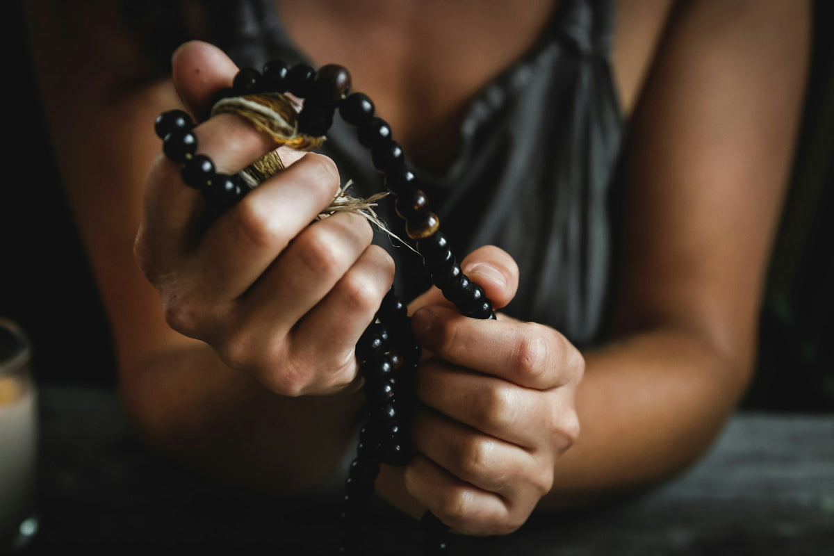 Hands counting the beads of a mala strand