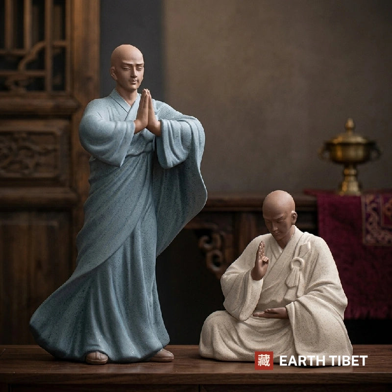 Two Chinese praying monk statues in purple clay ceramic, one standing with palms together and one seated