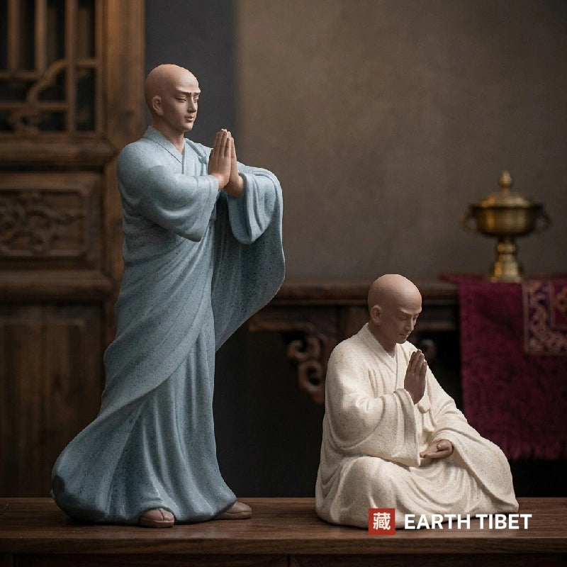 Praying monk statue shown beside a teapot on a tea table