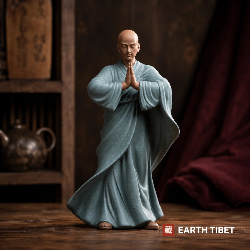 Standing Chinese praying monk statue in a blue-grey robe caught mid-step