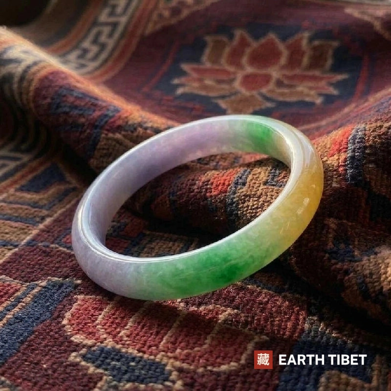 Lavender, green and yellow bangle resting on a Tibetan rug