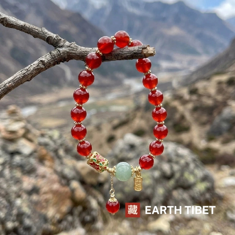 Red agate beads backlit on a branch, glowing translucent against a mountain valley