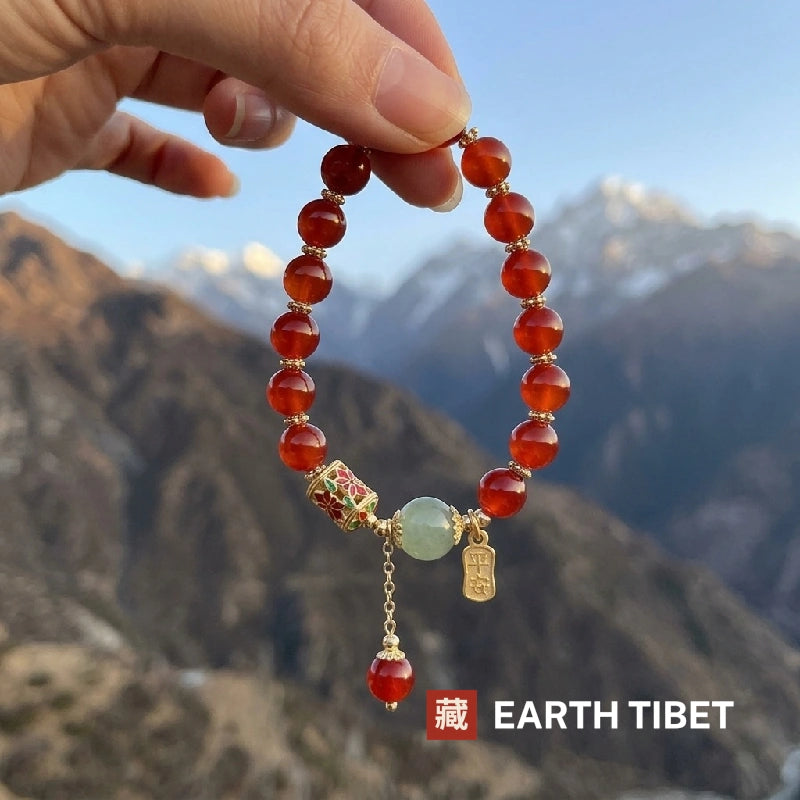 Cloisonne red agate bracelet held up against Himalayan peaks at dusk