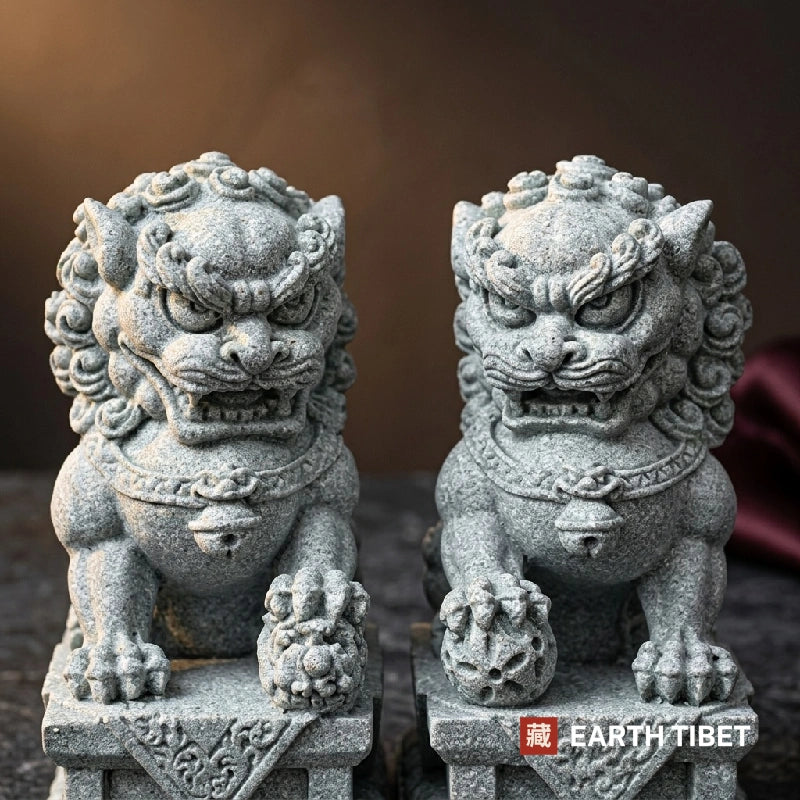 Close view of two sandstone guardian lion heads showing curled manes and collar bells