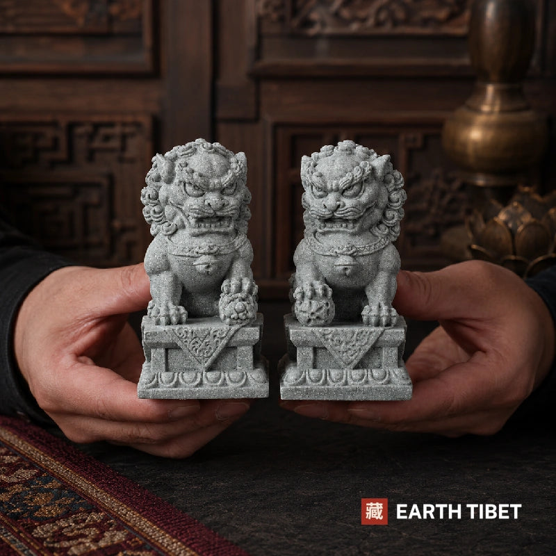 Chinese fu dog statue pair in grey-green sandstone on a dark surface