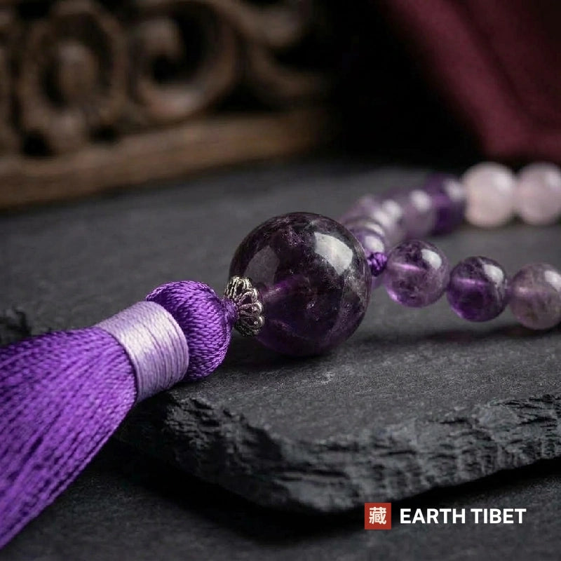 Close view of the large amethyst guru bead above the purple silk tassel