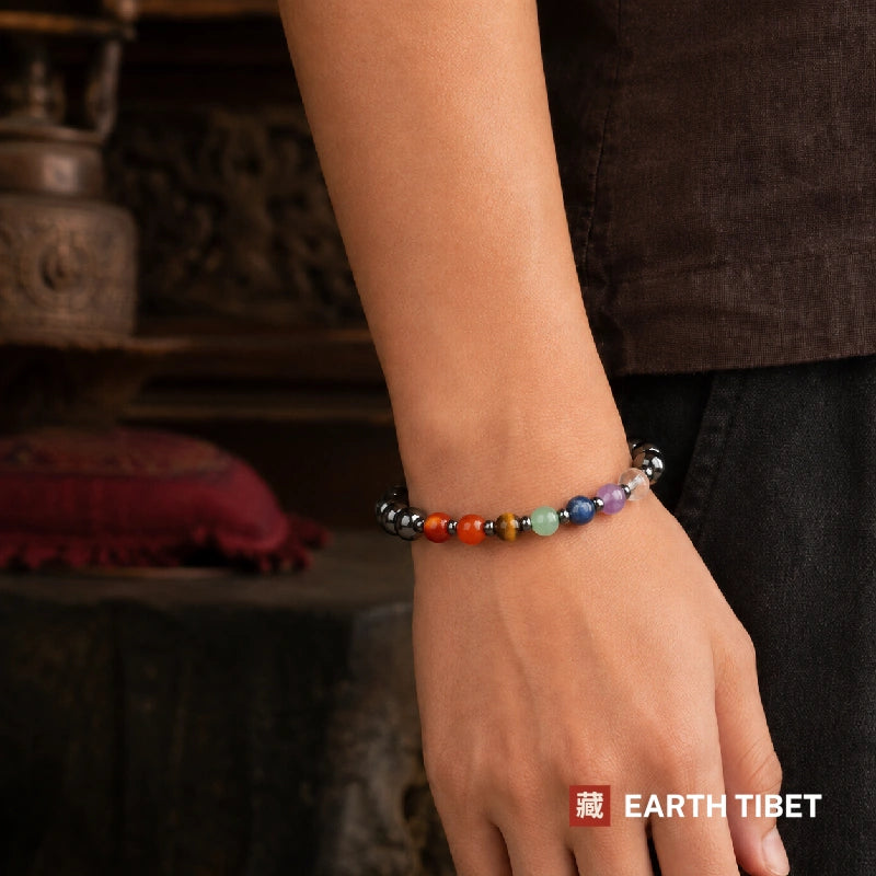 Seven chakra hematite bracelet worn on a wrist against a dark shirt