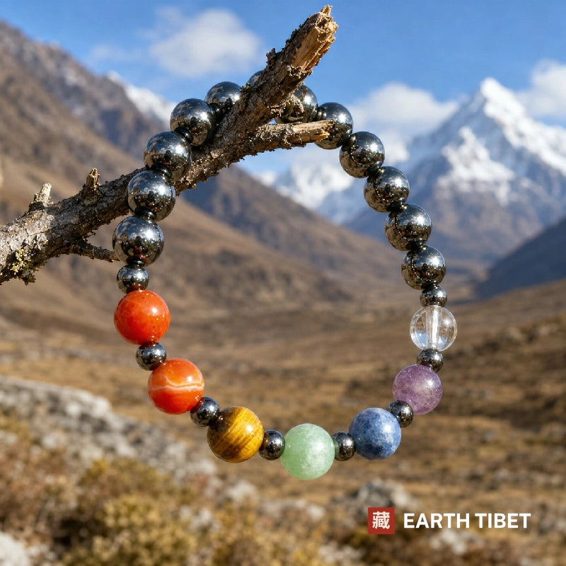 Seven chakra hematite bracelet hanging on a branch against Himalayan mountains