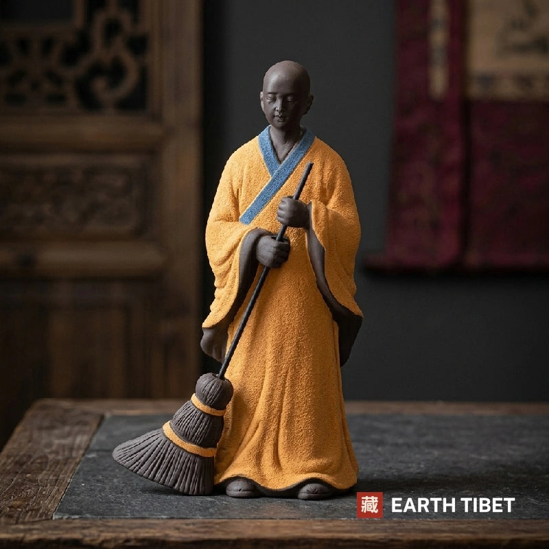 Front view of the sweeping monk statue holding a clay broom, eyes lowered