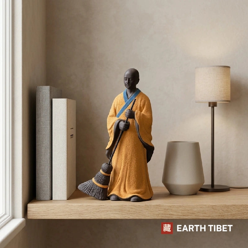 Sweeping monk statue styled on a shelf beside books, a vase and a lamp