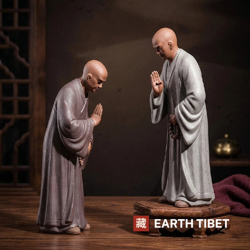 Two tall zen monk statues facing each other, one standing on a carved wooden base