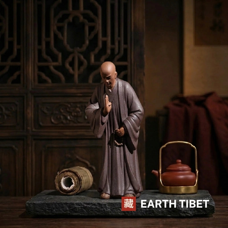Brown ceramic zen monk statue on slate with a bamboo scroll and a clay teapot