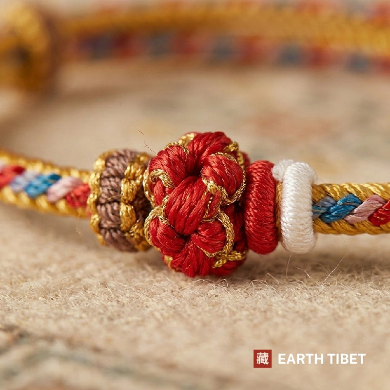 Close view of the red knotted bead wrapped in gold thread on the cord bracelet