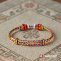 Gold protection cord bracelet with red knotted beads, seen from the front