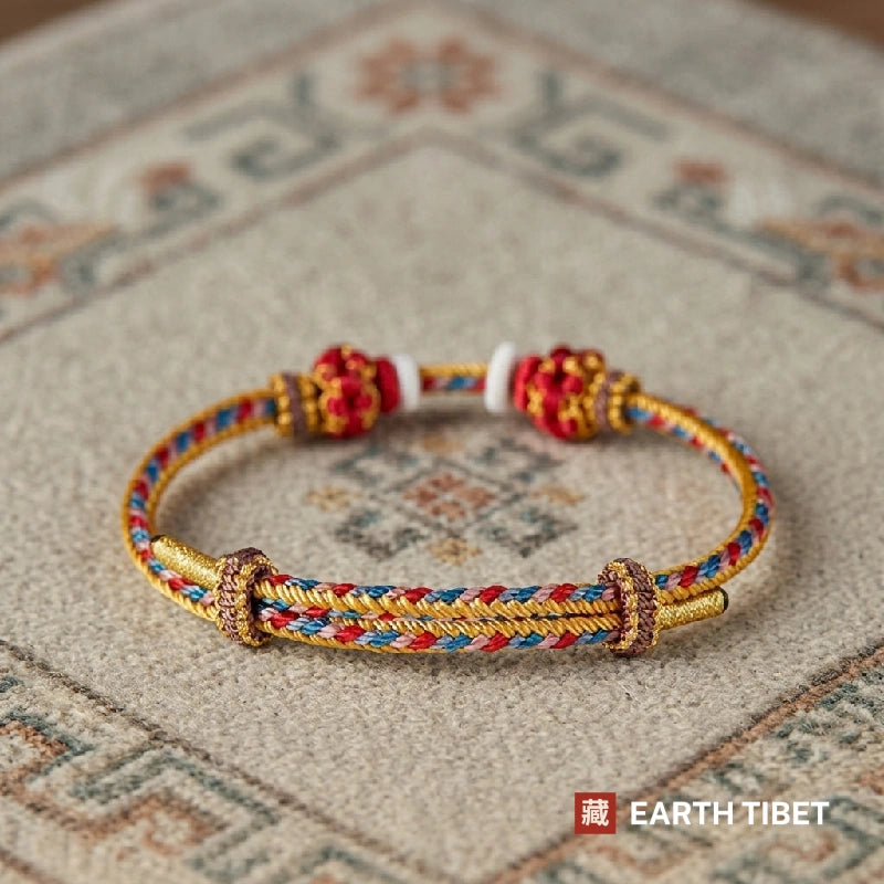Gold protection cord bracelet with red knotted beads, seen from the front
