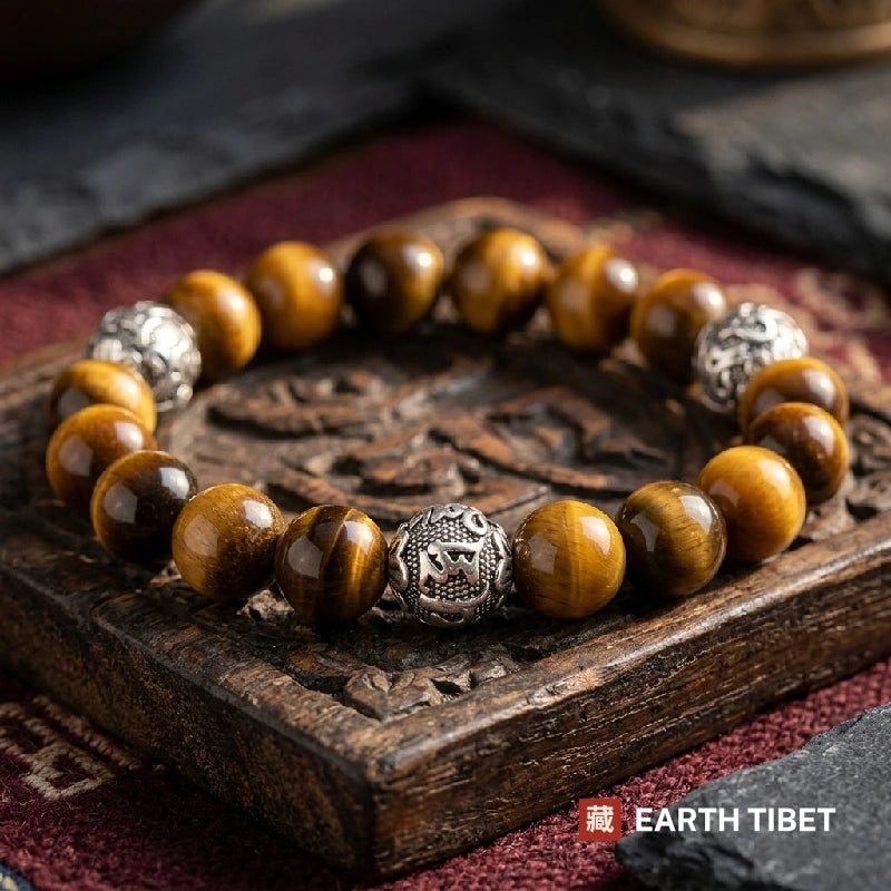 Tiger eye bracelet with three silver Om Mani Padme Hum beads on a carved wooden tray