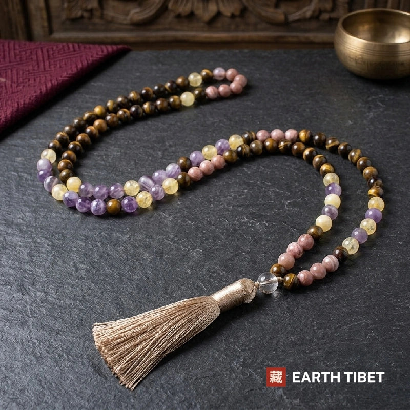 Full length of the sunstone tiger eye mala laid out on slate beside a singing bowl