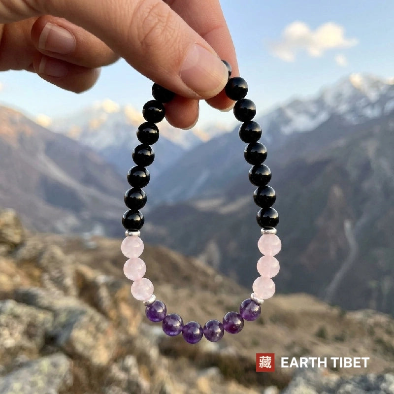 Black tourmaline amethyst and rose quartz bracelet held up in front of mountains
