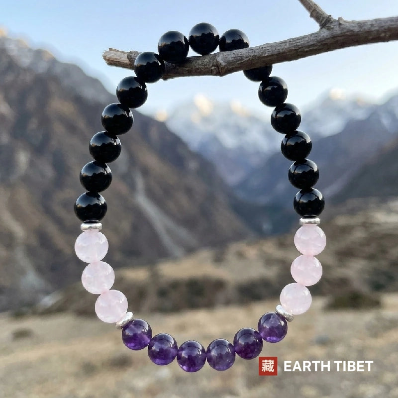 Protection bracelet of black tourmaline, rose quartz and amethyst hanging from a branch