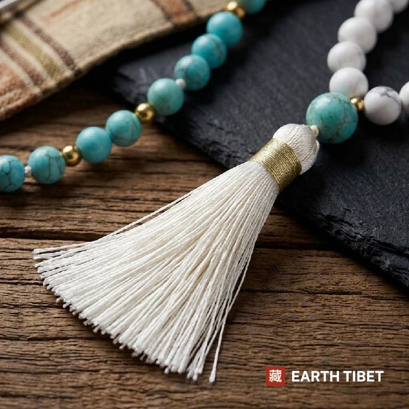 White silk tassel bound in gold thread below the turquoise guru bead