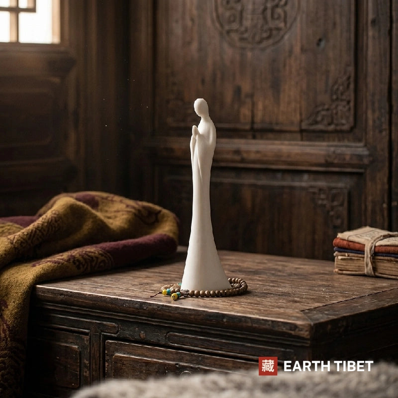 White faceless zen monk statue on an old wooden cabinet, head bowed and palms joined