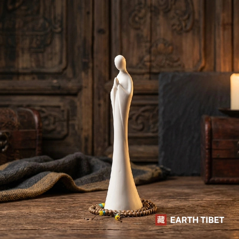 Front view of the faceless white zen statue, its robe flaring into a bell-shaped base