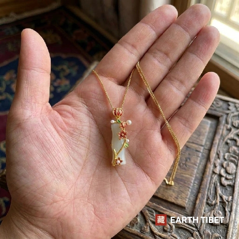 White chalcedony bamboo pendant and its chain lying in an open hand