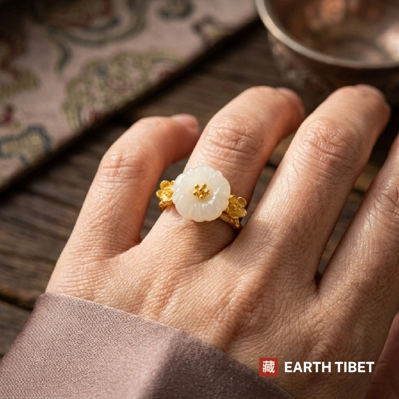 White blossom ring worn on a hand, with small gold plum flowers at the shoulders