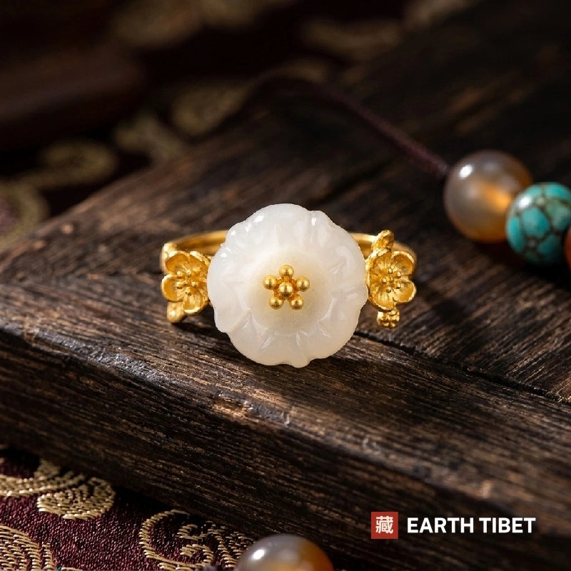 Carved white plum blossom ring with a gold stamen cluster on a wooden surface