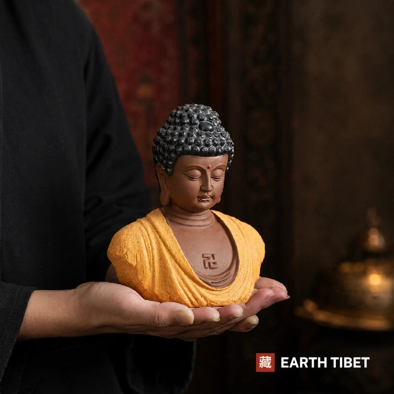 Ochre Buddha head statue held in one open palm to show its size