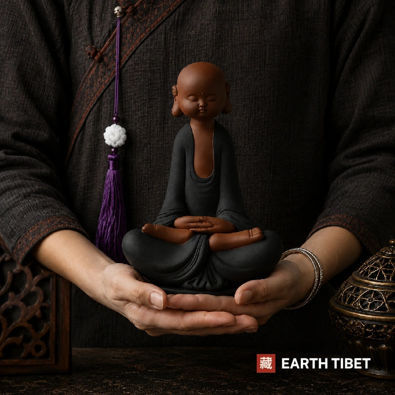 Purple clay monk statue on a wooden tea table beside a teapot